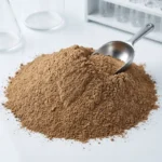 A professional close-up of fine, earthy-brown Mugwort Extract powder piled on a clean white laboratory surface with a stainless steel measuring scoop.