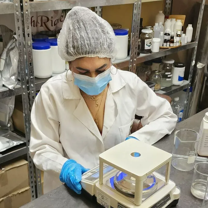 Sharika Regchand weighing ingredients on a scale while formulating skincare in the ShaRique lab